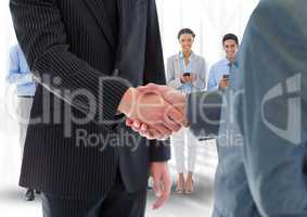 Composite image of Handshake in front of business people in office
