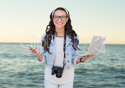 Composite image of Woman with phone and laptop in front of sea