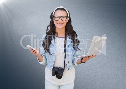 Woman with phone, laptop and camera against navy background with flare