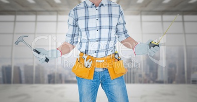 Carpenter with hammer and measuring tape against window