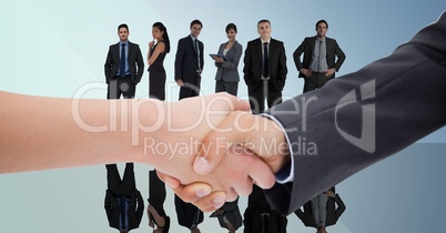 Composite image of Handshake in front of business people with blue background