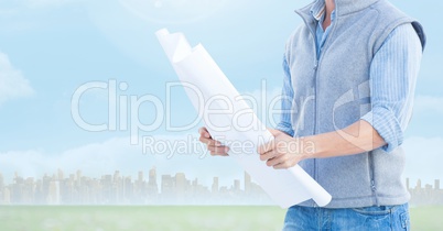 Architect Torso holding plan against city background