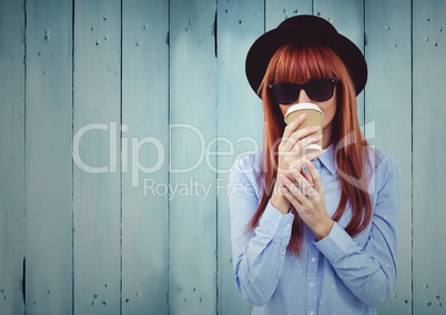 Woman with coffee and hat against blue wood panel