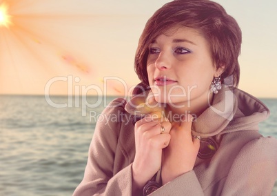 Composite image of Woman in coat against sea with flare