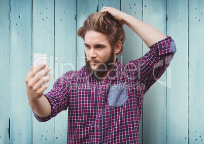 Man taking selfie against blue wood panel background