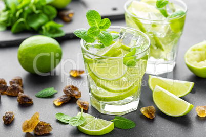 Summer mint lime refreshing cocktail mojito with rum and ice in glass on black background top view