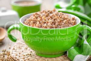 Fresh boiled buckwheat porridge and raw grain on wooden rustic table