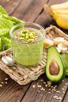 Avocado and banana smoothie with oats with ingredients in glass jar on wooden background, healthy eating