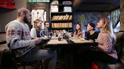 Young friends making stack of smart phones in cafe