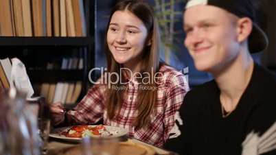 Cheerful teens enjoying meal sitting at cafe table