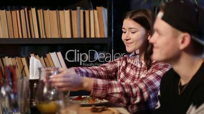 Attractive girl passing carafe with juice in cafe