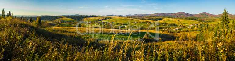 Village and autumn forest in mountains panorama.