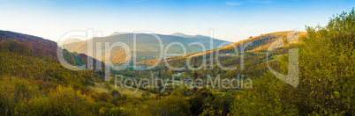 Mountains and autumn forest and blue sky panorama.