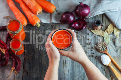 Iron mug with carrot juice in female hands