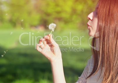 woman blowing on a dandelion