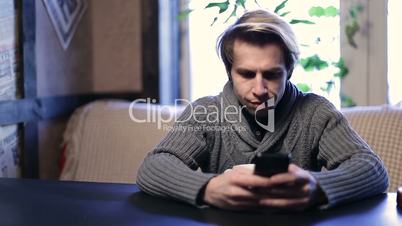 Cheerful young man texting on his smartphone