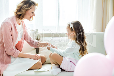 Girl putting jewelry on mother