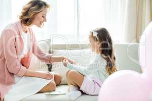 Girl putting jewelry on mother