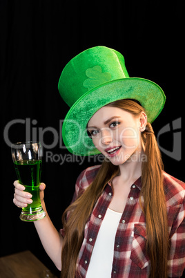 smiling woman holding glass of beer in hand on St.Patrick's day on black