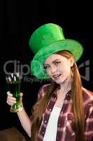 smiling woman holding glass of beer in hand on St.Patrick's day on black