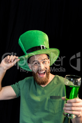 portrait of excited man holding glass of beer on St.Patrick's day on black