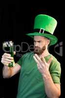 Portrait of upset man holding glass of beer on St.Patrick's day on black