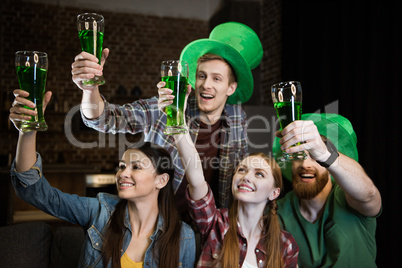 cheerful friends holding glasses with beer on St. Patrick's day celebration