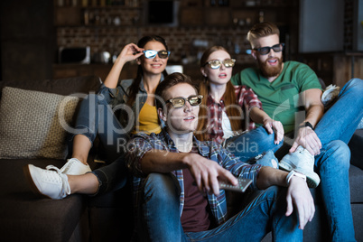 young friends in 3D glasses watching movie at home