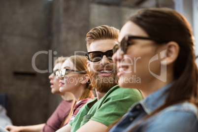 side view of concentrated and smiling friends in 3D glasses watching movie