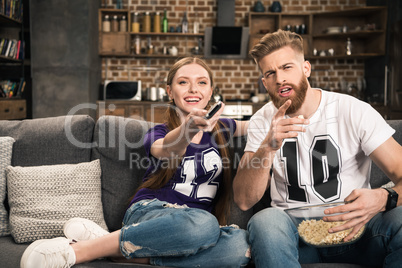 portrait of couple sitting on sofa and discussing movie at home