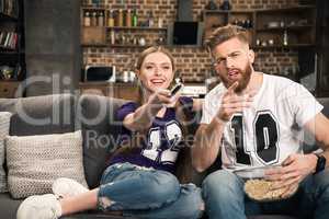 portrait of couple sitting on sofa and discussing movie at home