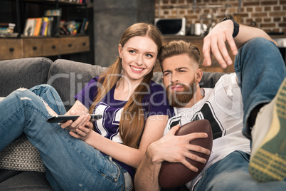 portrait of stylish man and woman watching sports game at home