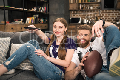 portrait of happy stylish couple watching sports game at home