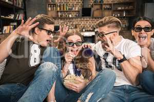 excited friends in 3D glasses watching movie at home