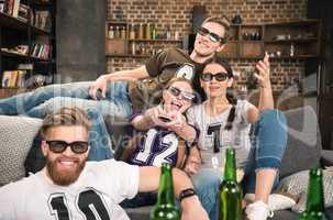 happy young friends in 3D glasses watching movie on sofa at home