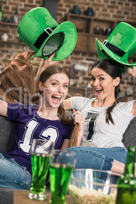 excited young women in green hats celebrating st patricks day