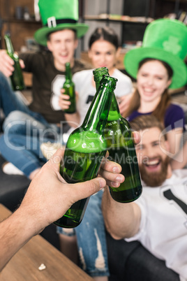 Close-up view of friends clinking beer bottles, st patricks day concept