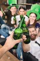 Close-up view of friends clinking beer bottles, st patricks day concept