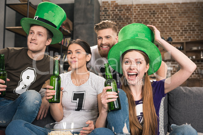 Happy young friends in hats drinking green beer and celebrating st patricks day