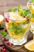 Lemon mojito cocktail with mint and pomegranate, cold refreshing drink or beverage