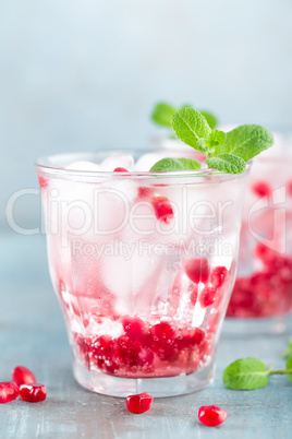 Infused water made of fresh pomegranate and mineral water with ice, cold refreshing and detox drink