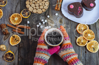 cup of black hot coffee in her hands, wearing colorful winter gl