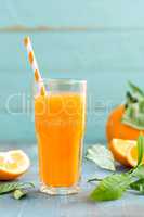 Orange juice in glass and fresh fruits with leaves on wooden background, vitamin drink or cocktail