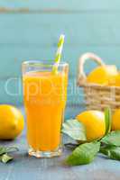 Lemon juice in glass and fresh fruits with leaves on wooden background, vitamin drink or cocktail