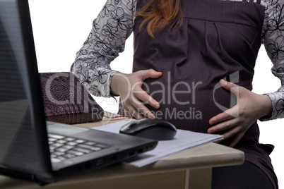 Pregnant woman hugging belly in office