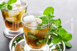 Mint Julep cocktail with bourbon, ice and mint in glass on black background