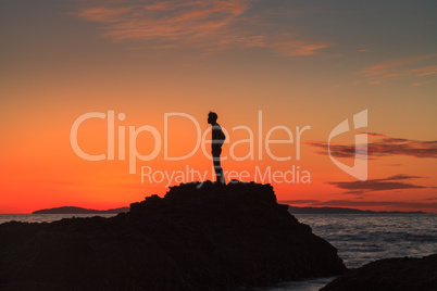 Silhouette of a man at sunset on a rock jetty