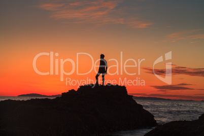 Silhouette of a man at sunset on a rock jetty