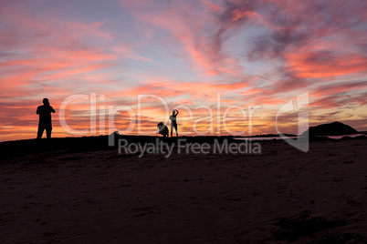 Silhouette of people enjoying the beach at sunset