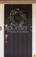 Black door with white trim and a purple, blue and green heather wreath